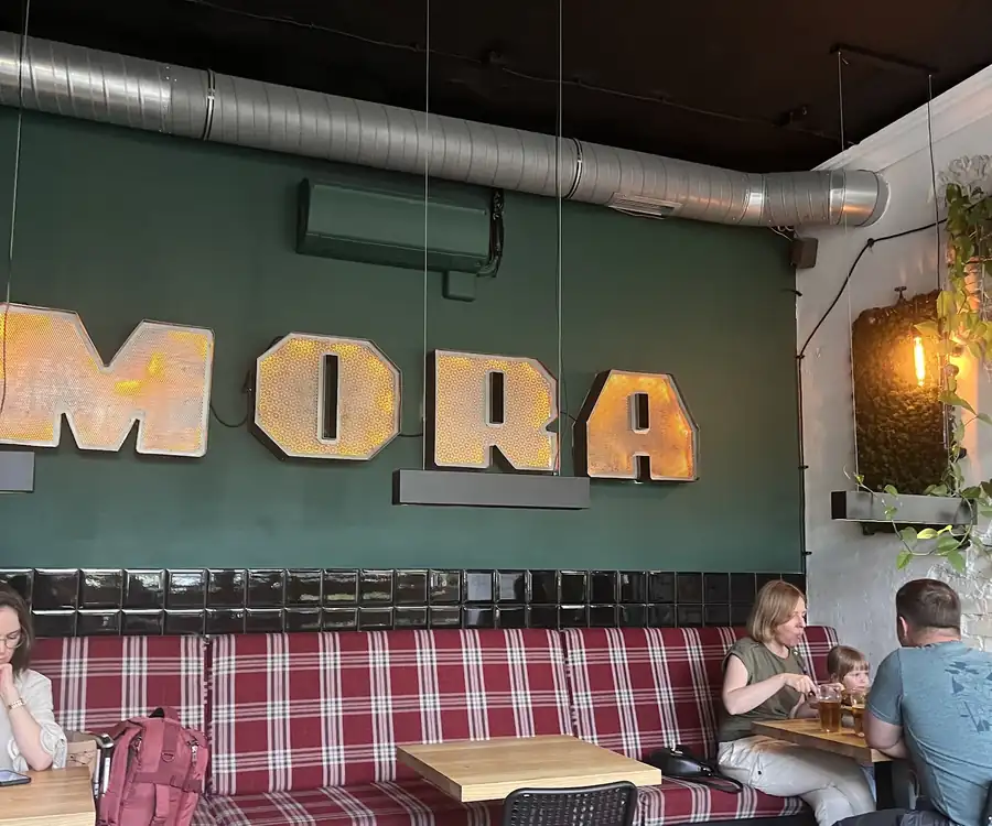 Wnętrze z napisem MORA i ławami w kratę