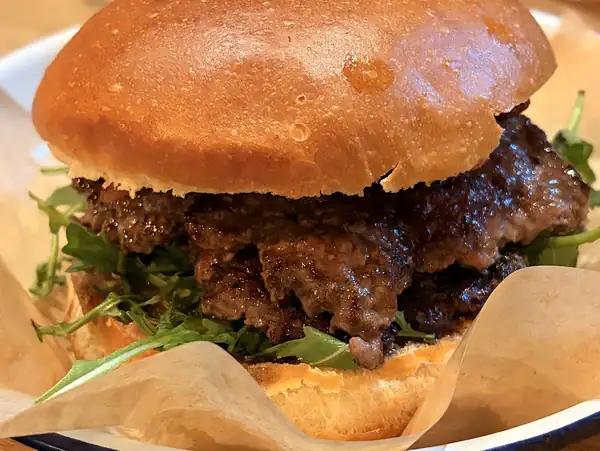 Burger z wołowiną w maślanej bułce na emaliowanym talerzu
